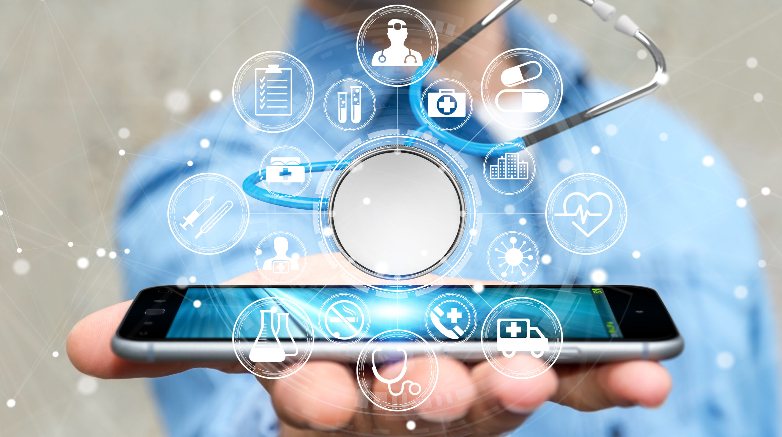 A hand holding a smartphone with healthcare icons, including a stethoscope, and symbols of advanced nurse call systems displayed holographically above it.